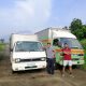 two men pose by an isuzu elf and a smaller container van